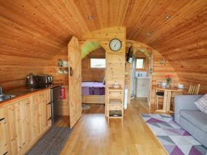 a kitchen and living room of a log cabin with a clock at Pine Lodge in Llangadog