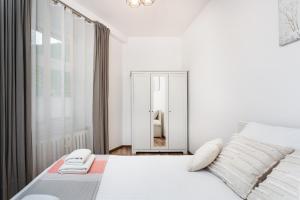 a white bedroom with a bed and a mirror at City of the Kings-Camomile Apartment in Krakow