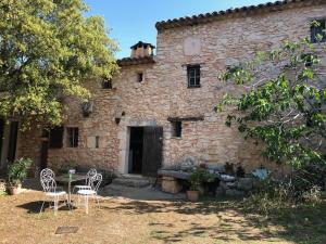 ein Gebäude mit zwei Stühlen und einem Tisch davor in der Unterkunft Le Jas des aiguiers in Saint-Saturnin-dʼApt