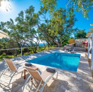a swimming pool with two chairs and a table with at Olive Cottage in Petrátika