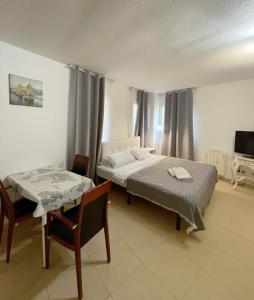 1 dormitorio con cama, mesa y TV en Royal Inn Aparthotel, en Lloret de Mar