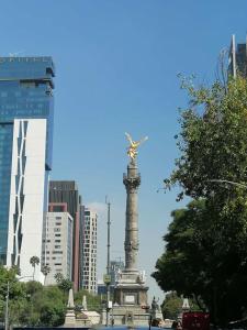 Una statua nel mezzo di una città con edifici di Departamento céntrico a una cuadra del Ángel de la Independencia a Città del Messico