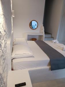 a white bedroom with two beds and a mirror at Traditional house under the castle in Astypalaia Town