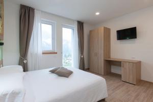 een hotelkamer met een wit bed en een raam bij Alle Arce in Domegge di Cadore