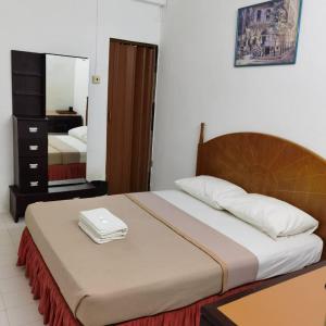 ein Schlafzimmer mit einem Bett mit einem Kopfteil aus Holz in der Unterkunft Padua inn in Batu Feringgi