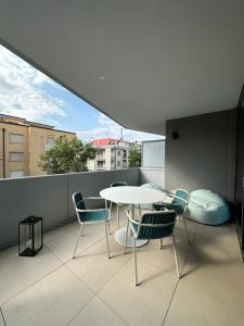 un balcon avec une table et des chaises blanches dans l'établissement Aparthotel Zefiro com design, large terrace, bike, near beach and thermal, à Grado