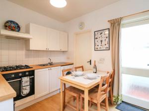 a kitchen with a table and chairs and a kitchen with white cabinets at Pixie Cottage in Weymouth