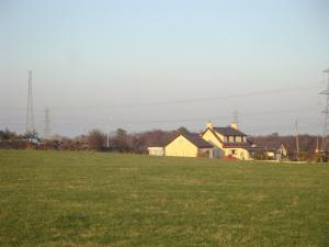Groeslon Ty Mawr B & B في Llanddeiniolen: حقل من العشب الأخضر مع منزل في الخلفية