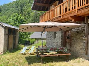 einem Picknicktisch mit einem Sonnenschirm vor einem Haus in der Unterkunft La Grange d'Anaïs in Beaufort