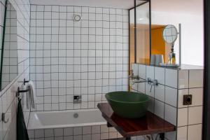 uma casa de banho com uma tigela verde numa mesa ao lado de uma banheira em De 6 Linden Boutique Hotel em Sluis