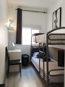 a bedroom with bunk beds and a desk and a chair at Vilapicina Hostal in Barcelona