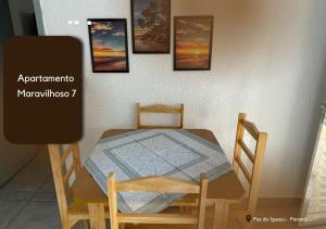 a wooden table and chair with a table and pictures on the wall at APARTAMENTO MARAVILH... 7 in Foz do Iguaçu
