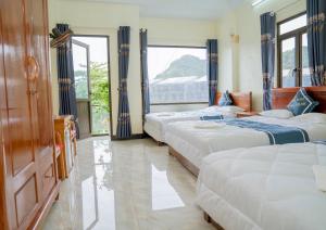 fila de camas en una habitación con ventanas en Long Thành Motel en Cat Ba