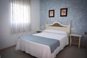 sypialnia z dużym białym łóżkiem i oknem w obiekcie Apartamentos Turísticos Cabo Roche w mieście Conil de la Frontera
