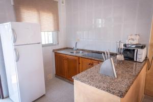 cocina con nevera blanca y fregadero en Apartamentos Turísticos Cabo Roche, en Conil de la Frontera