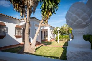 una casa bianca con palme in cortile di Apartamentos Turísticos Cabo Roche a Conil de la Frontera