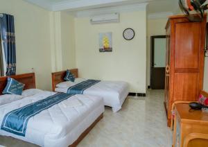 um quarto de hotel com duas camas e um relógio na parede em Long Thành Motel em Ilha de Cát Bà