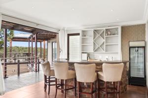 cocina con barra con sillas y balcón en Elements Private Golf Reserve House 197, en Bela-Bela