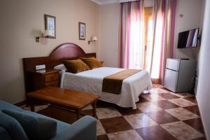 1 dormitorio con cama, mesa y sofá en Hostal Cabo Roche, en Conil de la Frontera