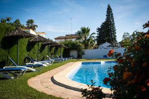 a swimming pool with lounge chairs next to a house at Hostal Cabo Roche in Conil de la Frontera