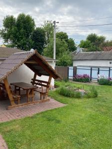 a wooden picnic table in a yard with a roof at Домик для отдыха рядом Днепр in Cherkasy