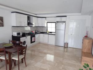 a kitchen with white cabinets and a table and a table and chairs at Stone House Aparts 2 plus 1 mit Poolterrasse Kalkan No 2 in Kalkan