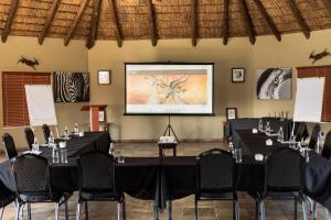 Una sala de conferencias con mesas, sillas y una pantalla. en Golden Impalas Bush Resort, en Hammanskraal 98 fotos más