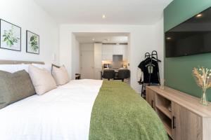 ein Schlafzimmer mit einem großen weißen Bett und einer grünen Decke in der Unterkunft Charming Studio in the Heart of Vibrant Brighton in Brighton & Hove