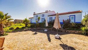 a patio with an umbrella and a house at Casa Presente Guesthouse in Carrapateira