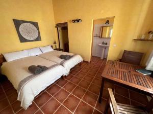 a bedroom with a large bed and a table at Casa Presente Guesthouse in Carrapateira