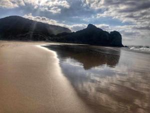 a view of a beach with mountains in the background at Casa Presente Guesthouse in Carrapateira
