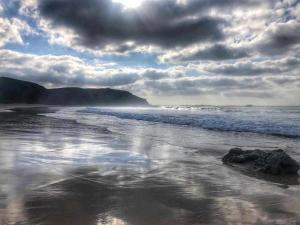 a beach with a cloudy sky and the ocean at Casa Presente Guesthouse in Carrapateira