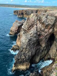 a rocky cliff in the ocean with the water at Casa Presente Guesthouse in Carrapateira