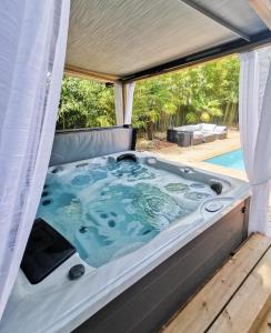 a jacuzzi tub in a tent next to a pool at Villa Moya, dependance privée Piscine & Spa in Châteauneuf-sur-Loire