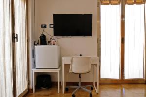 una scrivania con sedia e una TV appesa a un muro di Guest House Ancora a Pozzallo