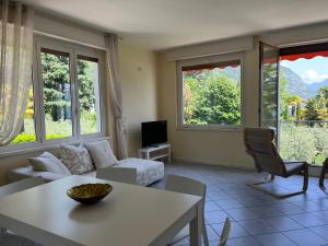 sala de estar con sofá, mesa y ventanas en Le luci sul lago, en Predore