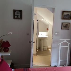 ein Bad mit einem Waschbecken und einer Tür zu einem Zimmer in der Unterkunft Gite de la Drouette et chambre d'hôtes in Villiers-le-Morhier