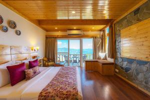 a bedroom with a large bed and a balcony at StayVista at Sarog Cottage at Daafi in Shimla