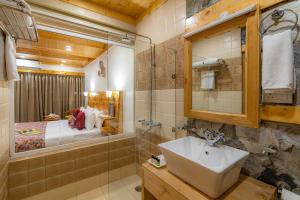 a bathroom with a sink and a shower and a bed at StayVista at Sarog Cottage at Daafi in Shimla