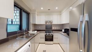 a kitchen with white cabinets and a stainless steel refrigerator at Key View - Maple 2 in Dubai