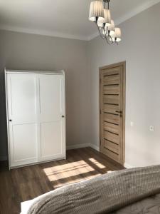 a bedroom with a bed and a closet and a chandelier at Vytauto Septyni in Zarasai