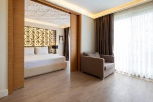 a bedroom with a bed and a chair and a window at Duja Didim - Ultra All Inclusive in Didim +174 photos