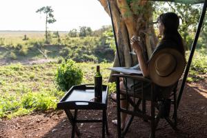 a woman sitting in a chair with a bottle of wine at Basecamp Adventure in Masai Mara