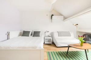 a white bedroom with two beds and a table at African heritage Tervuren in Tervuren