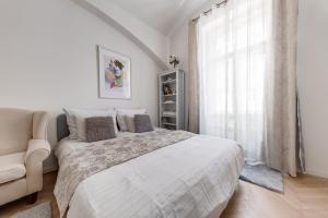 a white bedroom with a bed and a window at Apartments With The Lions in Prague