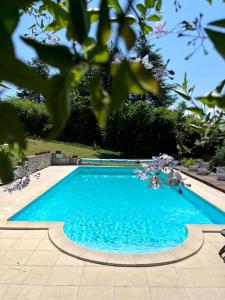a large blue swimming pool in a yard at La Colline de Tilleul - De La Colline - Beautiful Cottage Near Aubeterre in Saint-Romain