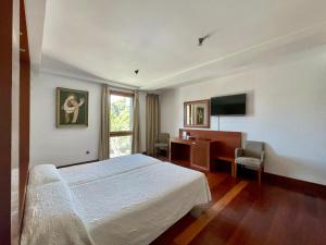 Schlafzimmer mit einem Bett, einem Schreibtisch und einem TV in der Unterkunft Acinipo in Ronda