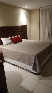 a bedroom with a large bed with a red pillow at Hotel Village Toritama in Toritama