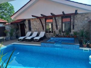 a swimming pool with chairs next to a house at Stariya oreh pool & garden in Vidin