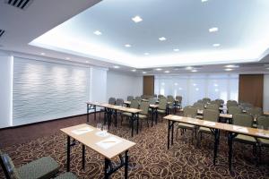 Hotel Europa Fit Hévíz في هفيز: قاعة اجتماعات مع طاولات وكراسي ونافذة كبيرة